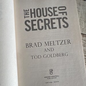 May include: Open book with the title "THE HOUSE OF SECRETS" in large, gray letters. The authors' names, Brad Meltzer and Tod Goldberg, are below. The Grand Central Publishing logo and city names are at the bottom.