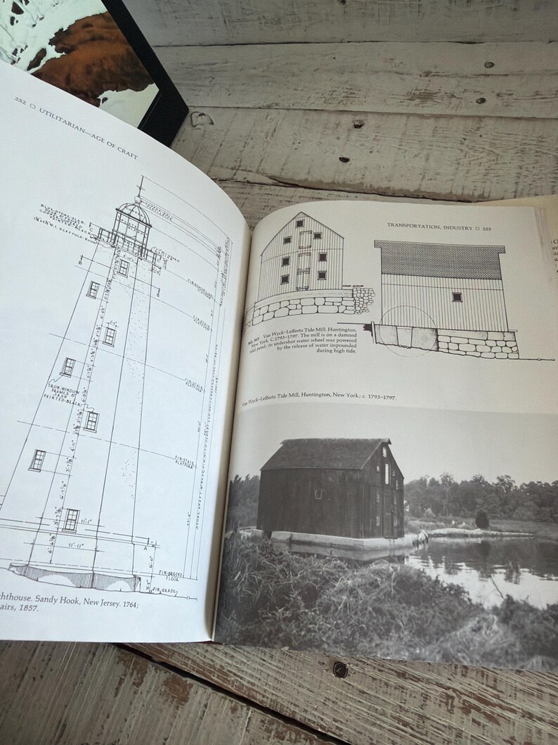 May include: An open book displaying black and white architectural drawings and a photograph of historical structures. The left page shows a technical diagram of a lighthouse in Sandy Hook, New Jersey. The right page features the Van Wyck-Lefferts Tide Mill.