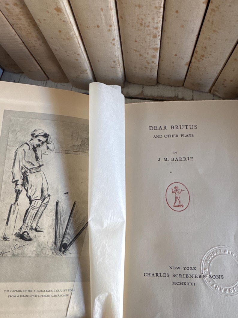 Puede incluir: Libro abierto titulado "DEAR BRUTUS AND OTHER PLAYS" de J.M. Barrie. La portada es blanquecina con texto negro. Un dibujo de un jugador de cr&iacute;quet est&aacute; en la p&aacute;gina izquierda. Publicado por Charles Scribner's Sons, Nueva York, MCMXXXI.