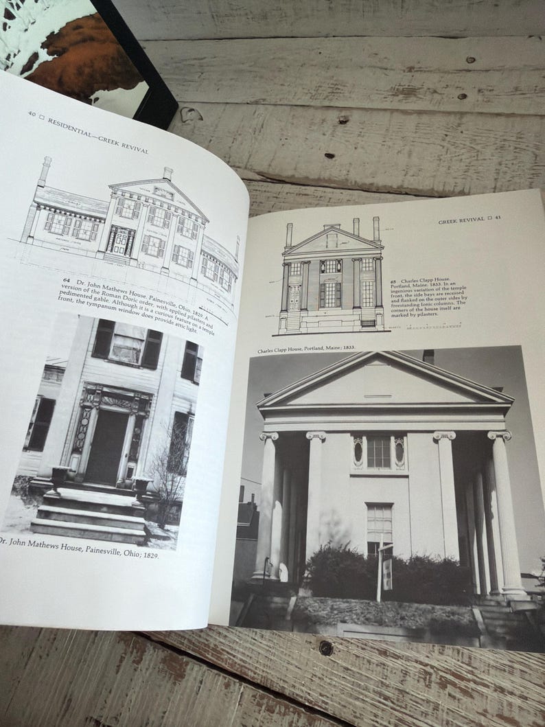 May include: An open book displaying black and white architectural illustrations and photographs of Greek Revival houses, including the Dr. John Mathews House and the Charles Clapp House, with descriptive text detailing the building designs.