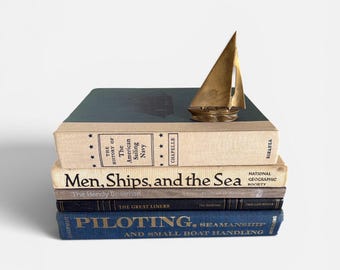 Libros de mesa de centro de gran formato con temática náutica, decoración de barcos o embarcaciones, adornos marítimos, decoración de interiores para casas de playa en tonos azules y beige.