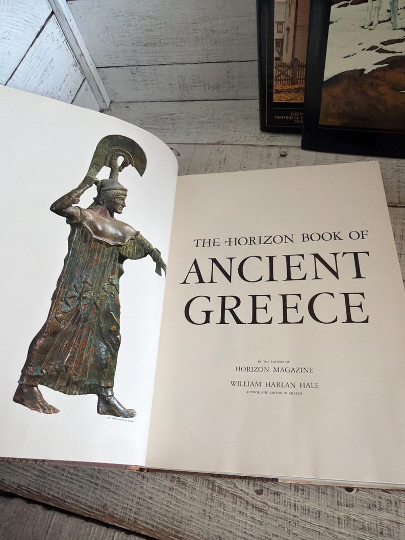 May include: An open hardcover book titled The Horizon Book of Ancient Greece by William Harlan Hale. The left page features a color illustration of a bronze statue of a figure in a helmet and robe, while the right page displays the title text.