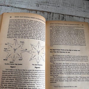 Puede incluir: Libro abierto con texto e ilustraciones sobre la Estrella de Ishtar. Las ilustraciones incluyen s&iacute;mbolos en forma de estrella y diagramas. El libro est&aacute; abierto sobre una superficie de madera. El texto est&aacute; en ingl&eacute;s.