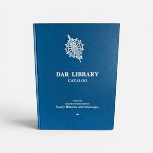 May include: A blue hardcover book titled DAR LIBRARY CATALOG, Volume One, SECOND REVISED EDITION, Family Histories and Genealogies, 1983. The cover features a white circular emblem of the Daughters of the American Revolution at the top center.