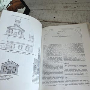 May include: An open book featuring architectural illustrations of churches on the left page and text titled 1840-1870 Early Victorian Gothic Revival on the right page. The black and white line drawings depict the Congregational Church and Zions Evangelical Church.