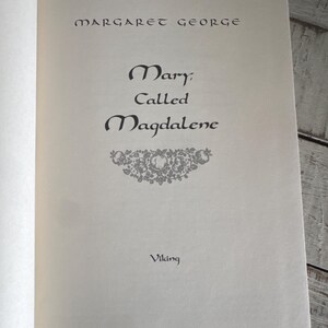 May include: Open book page with the title "Mary Called Magdalene" by Margaret George. The book's title is in a decorative font, with the publisher's name, Viking, at the bottom. The page is off-white.