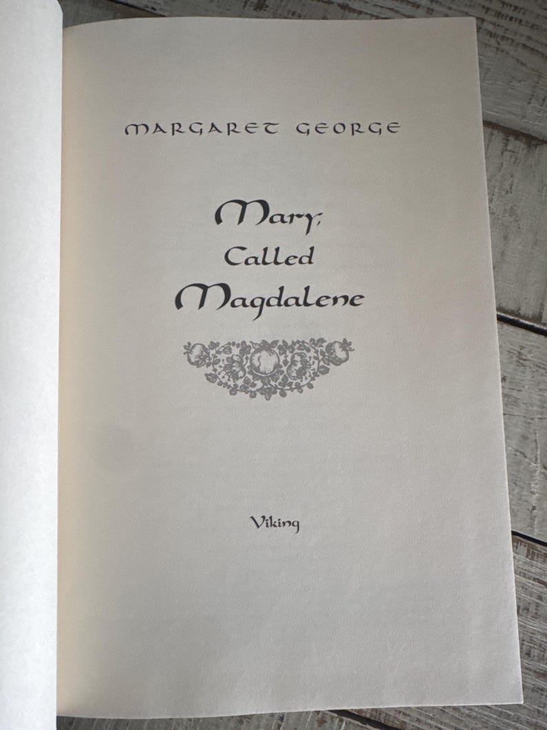 May include: Open book page with the title "Mary Called Magdalene" by Margaret George. The book's title is in a decorative font, with the publisher's name, Viking, at the bottom. The page is off-white.