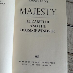 May include: An open book titled "MAJESTY" by Robert Lacey. The subtitle reads "ELIZABETH II AND THE HOUSE OF WINDSOR." Published by Harcourt Brace Jovanovich, with locations in New York and London. The book's pages are off-white.