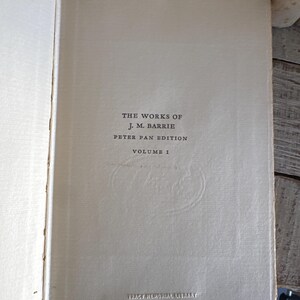 Puede incluir: Libro abierto que muestra la p&aacute;gina de t&iacute;tulo de "The Works of J.M. Barrie, Peter Pan Edition, Volume 1". El texto en negro sobre una p&aacute;gina color crema. Tambi&eacute;n aparece la inscripci&oacute;n "Tracy Memorial Library, New London, H.H.".