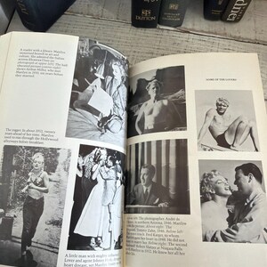 May include: An open book featuring black and white photographs of Marilyn Monroe. The book displays various images, including portraits and candid shots. Several books are visible in the background.