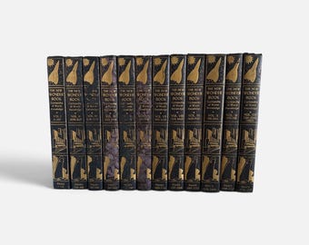 May include: A set of twelve black hardcover books titled The New Wonder Book Cyclopedia of World Knowledge. Each spine features gold-colored illustrations of a sun, a rocket, and architectural structures, with volume numbers and page ranges.