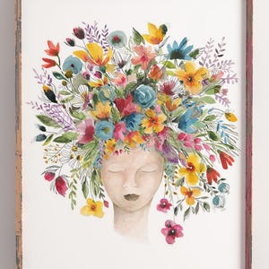 May include: Watercolor painting of a face with a crown of colorful flowers. The flowers are in shades of pink, purple, blue, yellow, and green. The face is closed-eyed and has a serene expression.
