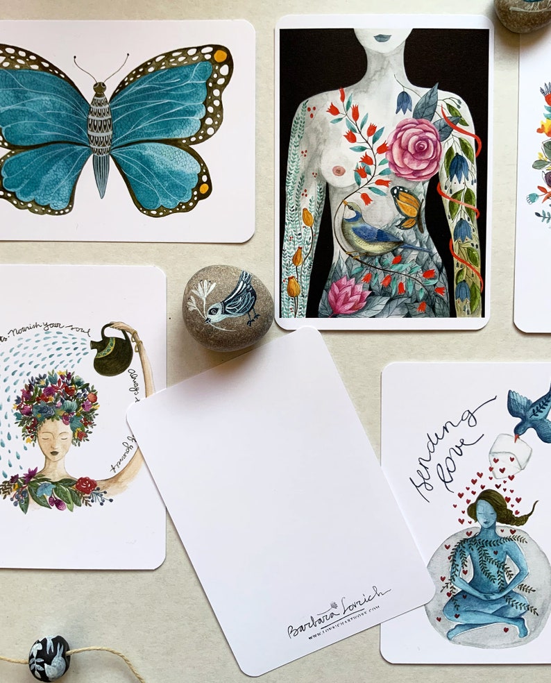 May include: Set of five illustrated cards featuring a blue butterfly, a woman's torso with floral and bird imagery, a woman with a flower crown, a blank card with the artist's name and website, and a woman meditating with a bird and hearts. The cards are printed on white cardstock and have a matte finish.