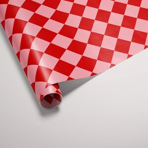 May include: A roll of red and pink checkered wrapping paper is partially unrolled, revealing the pattern. The paper is curled at the edge, creating a three-dimensional effect.