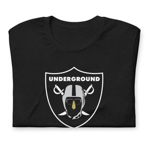 May include: Black t-shirt with a white graphic of a football helmet with sunglasses and crossed swords. The text "UNDERGROUND" is above the helmet.
