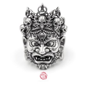 K&ouml;nnte beinhalten: Ein silberner Ring mit einem detaillierten Design eines D&auml;monengesichts mit einer Krone aus Sch&auml;deln. Der Ring ist aus Sterlingsilber gefertigt und hat eine hochgl&auml;nzende Oberfl&auml;che.