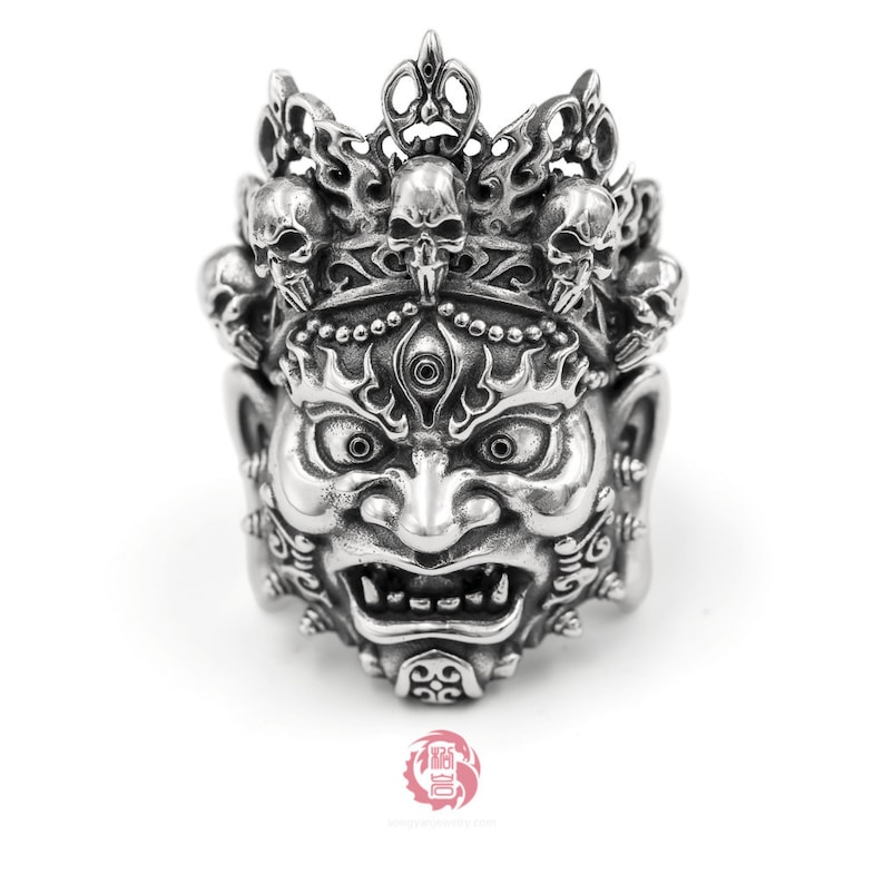 K&ouml;nnte beinhalten: Ein silberner Ring mit einem detaillierten Design eines D&auml;monengesichts mit einer Krone aus Sch&auml;deln. Der Ring ist aus Sterlingsilber gefertigt und hat eine hochgl&auml;nzende Oberfl&auml;che.