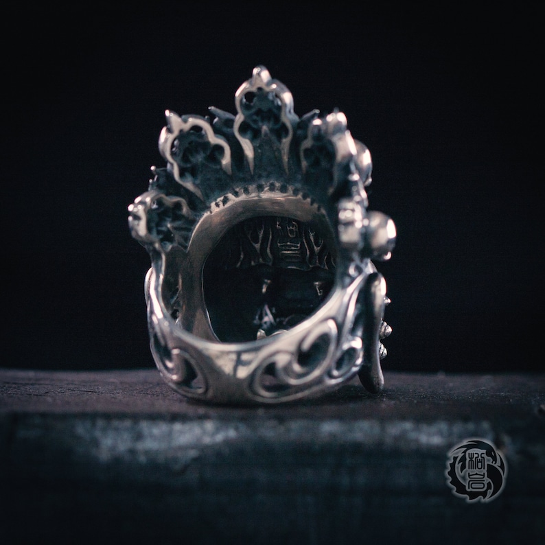 K&ouml;nnte beinhalten: Ein silberner Ring mit filigranen Details und einem kronenartigen Design. Der Ring ist aus Metall und hat ein detailliertes Design.
