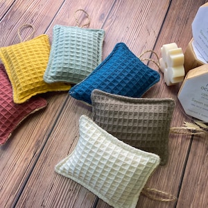 May include: Six different colored waffle weave dishcloths with a loop for hanging. The dishcloths are in shades of red, yellow, blue, green, brown, and white. The dishcloths are arranged in a row on a wooden surface. The dishcloths are made of natural fibers and are eco-friendly.
