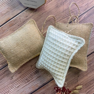May include: Three dishcloths, two are made of burlap and one is white with a waffle texture. The dishcloths are on a wooden surface. The dishcloths are hanging from a string. A small yellow box with the text "Octobulle 100% naturel Detergent Savon vaisselle Sans huile essentielle Fabriqu&eacute; &agrave; Bordeaux" is in the upper left corner of the image.