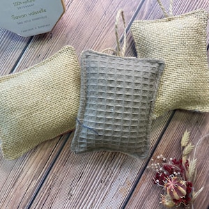May include: Three dishcloths, two are made of natural burlap and one is a gray waffle weave. The dishcloths are hanging from a string.