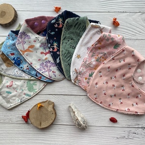 Puede incluir: Un conjunto de diez baberos para bebé coloridos con varios patrones, incluyendo animales, flores y diseños geométricos. Los baberos están hechos de tela suave y absorbente y tienen un respaldo impermeable.