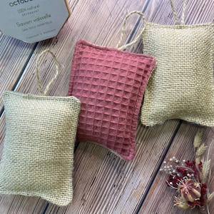 May include: Four dishcloths, two are beige and made of burlap, and two are a reddish-brown color and made of a waffle weave fabric. The dishcloths are hanging from a string loop.
