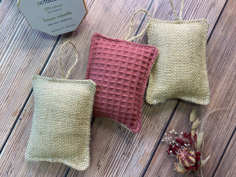 May include: Four dishcloths, two are beige and made of burlap, and two are a reddish-brown color and made of a waffle weave fabric. The dishcloths are hanging from a string loop.