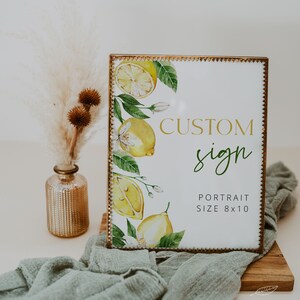 May include: A gold-framed sign with a watercolor illustration of lemons and blossoms. The sign reads "CUSTOM sign PORTRAIT SIZE 8x10" and "GOLDEN LEAF PAPERIE".