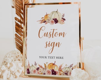 May include: A gold framed sign with a white background. The sign features watercolor pumpkins, flowers, and foliage. The words "Custom sign" are written in a copper-colored script, with "YOUR TEXT HERE" below.