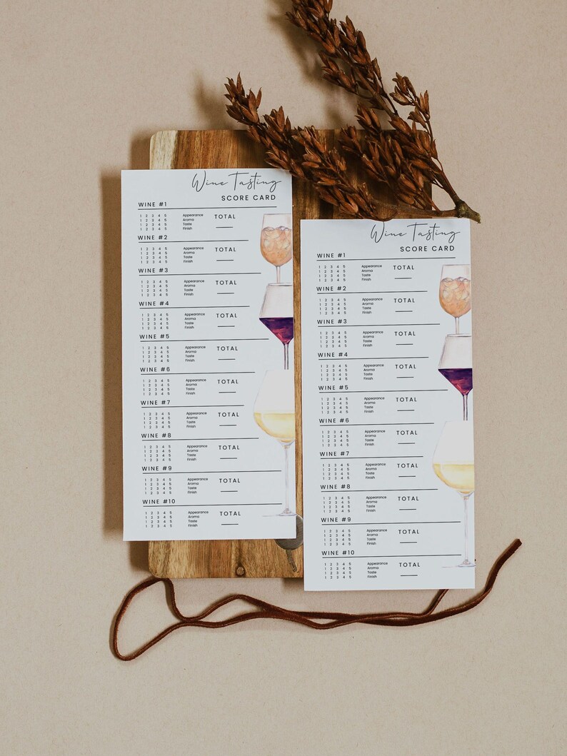 May include: Two white wine tasting score cards with watercolor illustrations of wine glasses, displayed on a wooden board. The cards have the text "Wine Tasting Score Card" at the top and space to rate ten wines.