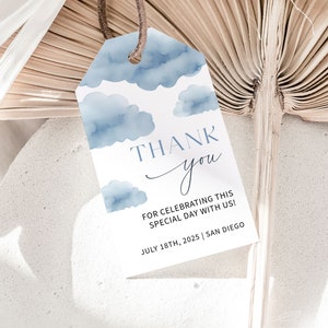 May include: A white thank you tag with a blue watercolor cloud design. The text reads "THANK you" with a handwritten "you". The tag also includes the text "FOR CELEBRATING THIS SPECIAL DAY WITH US! JULY 18TH, 2025 | SAN DIEGO"