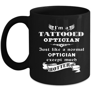 May include: Black coffee mug with white text that reads "I'm a Tattooed Optician Just like a normal Optician except much hotter".