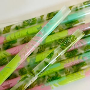 May include: A set of clear plastic drinking straws with a tropical leaf pattern in shades of green, pink, and blue.