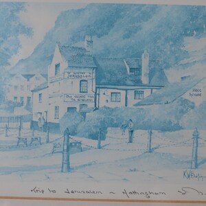 May include: A blue and white monochromatic print depicting the Ye Olde Trip to Jerusalem inn in Nottingham. The artwork features the building facade with text reading Ye Olde Jerusalem and The Oldest Inn In England, signed by the artist K.W. Burton.