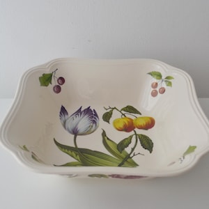 May include: A square, cream-coloured ceramic bowl with scalloped edges. The interior features a botanical illustration of a purple and white tulip, two yellow and red apples on a branch, and small clusters of cherries with green leaves.