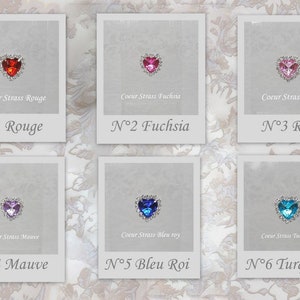 May include: Six heart-shaped rhinestones with different colored crystals, each displayed in a white frame with a silver border. The frames are labeled with the color of the rhinestone and a number. The colors are red, fuchsia, pink, mauve, blue, and turquoise.