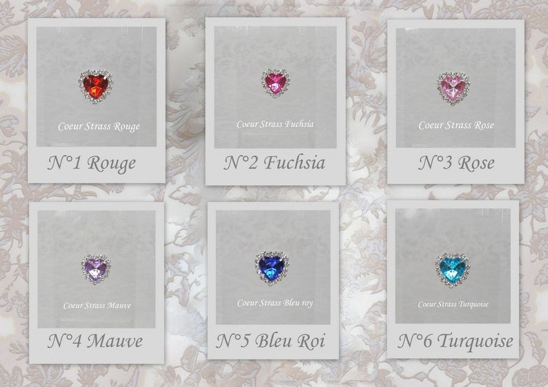 May include: Six heart-shaped rhinestones with different colored crystals, each displayed in a white frame with a silver border. The frames are labeled with the color of the rhinestone and a number. The colors are red, fuchsia, pink, mauve, blue, and turquoise.