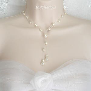 May include: A delicate pearl necklace with a Y-shaped design. The necklace features multiple small pearls strung along a clear, thin cord, with a larger pearl pendant. The necklace is displayed on a mannequin.