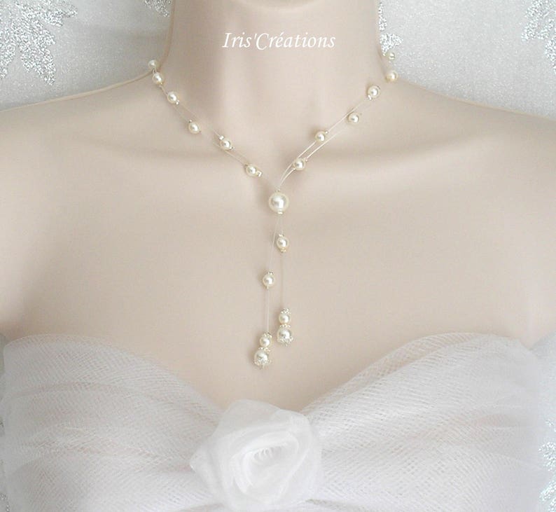 May include: A delicate pearl necklace with a Y-shaped design. The necklace features multiple small pearls strung along a clear, thin cord, with a larger pearl pendant. The necklace is displayed on a mannequin.