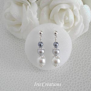 Peut inclure: Boucles d'oreilles pendantes argentées avec trois perles en nuances de gris et de blanc.