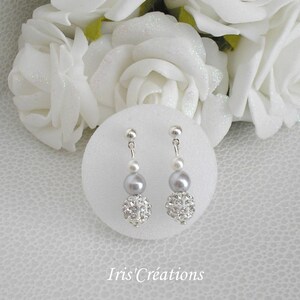 Peut inclure: Une paire de boucles d'oreilles pendantes argentées avec une petite perle, une perle grise et une boule argentée scintillante.