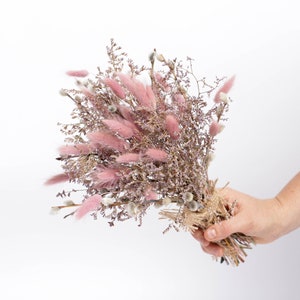 May include: A bouquet of dried flowers with pink bunny tails and purple sprigs tied with twine.