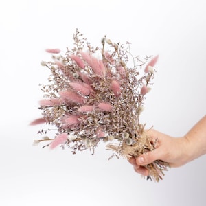 May include: A bouquet of dried flowers with pink bunny tails and purple sprigs tied with twine.