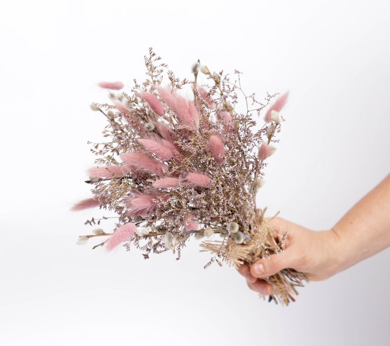 May include: A bouquet of dried flowers with pink bunny tails and purple sprigs tied with twine.
