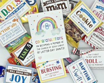 May include: A colorful card with a rainbow and clouds, congratulating someone on becoming a member of the Church of Jesus Christ of Latter-day Saints. The card is surrounded by small bags of candy with various religious-themed messages, such as "D.O.T.S. Depend on the Savior", "Take 5", "Sharing the Gospel Will Bring You Joy", "Smart Cookie", "Baptism is Sweet", and "Bursting with Excitement for You".