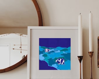 Può includere: Una stampa incorniciata bianca di un paesaggio astratto blu e verde con due mucche bianche e nere. La stampa è appesa a un muro bianco sopra un camino con due candelabri e candele.