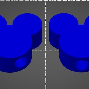 Op de afbeelding: Twee blauwe plastic Mickey Mouse-kopvormige bedels met een gat aan de onderkant.