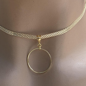 May include: A gold-toned necklace featuring a delicate, multi-strand woven chain that sits close to the neck. A simple, smooth, circular pendant is suspended from the center of the chain by a small, polished gold-toned triangular bail connector.