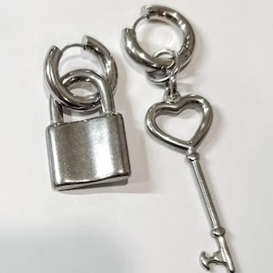 Peut inclure: Une paire de boucles d'oreilles en argent, l'une avec un pendentif en forme de cadenas et l'autre avec un pendentif en forme de clé de cœur.